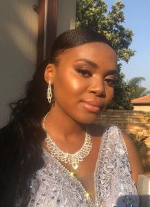 Young woman with dark hair in an embellished dress wearing matching silver jewelry outdoors.